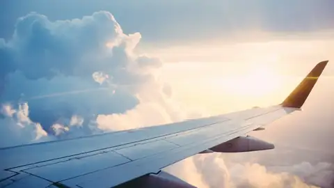 Aircraft wing above the clouds at sunrise